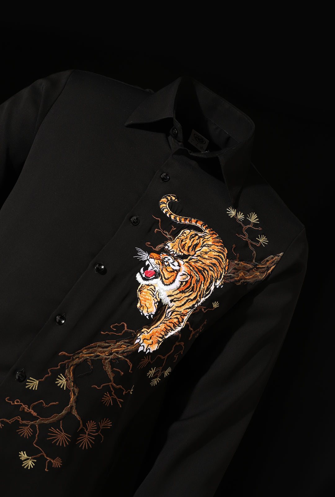 Black shirt with a tiger embroidered on a branch against a black background